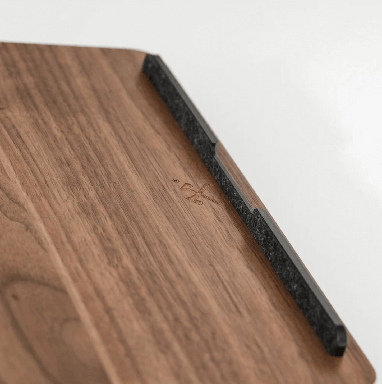 Close-up of wooden laptop stand surface with carved detail and black edge support