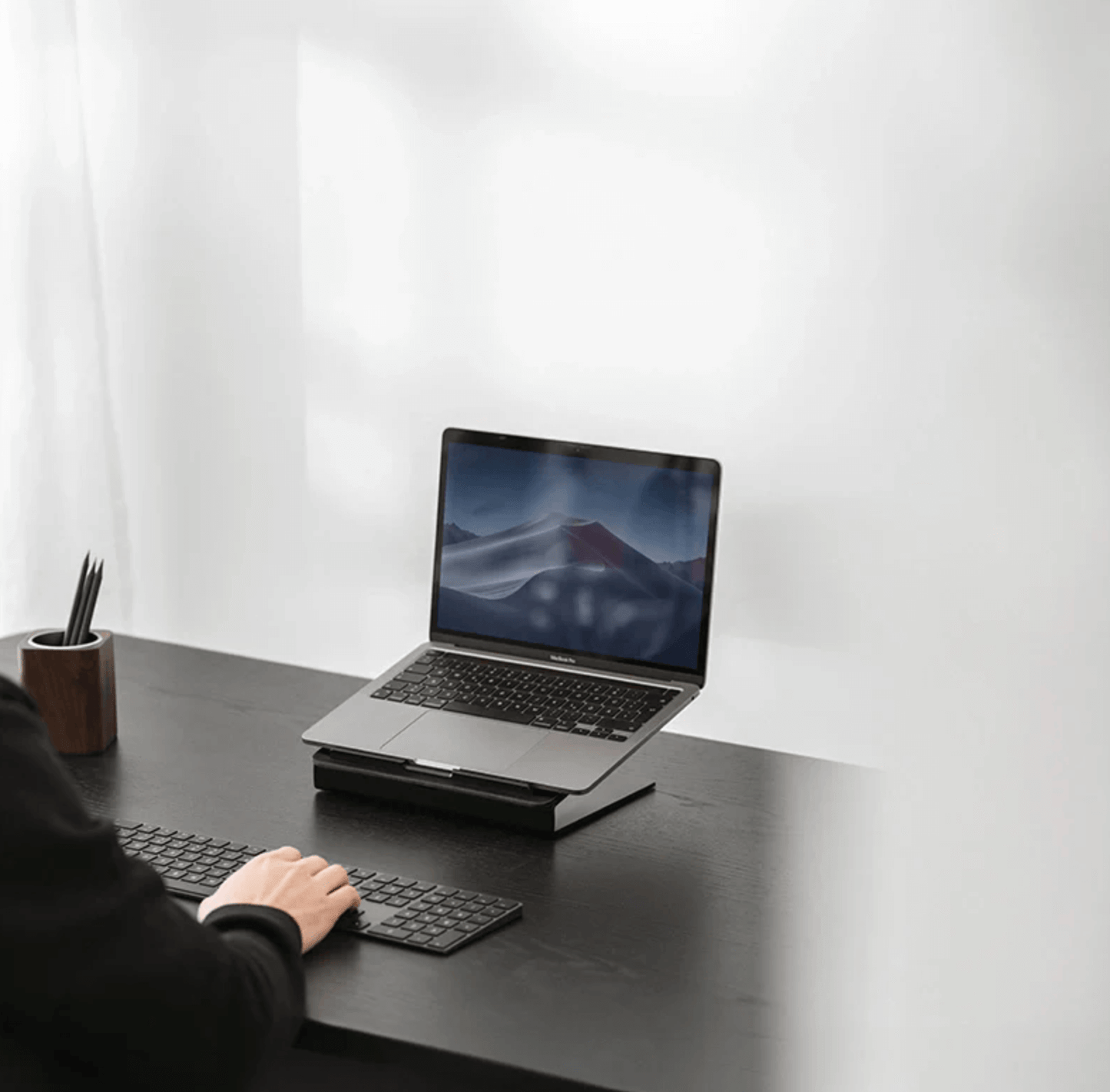 Classic laptop stand on a desk with a person using a keyboard. laptop stands, laptop riser,