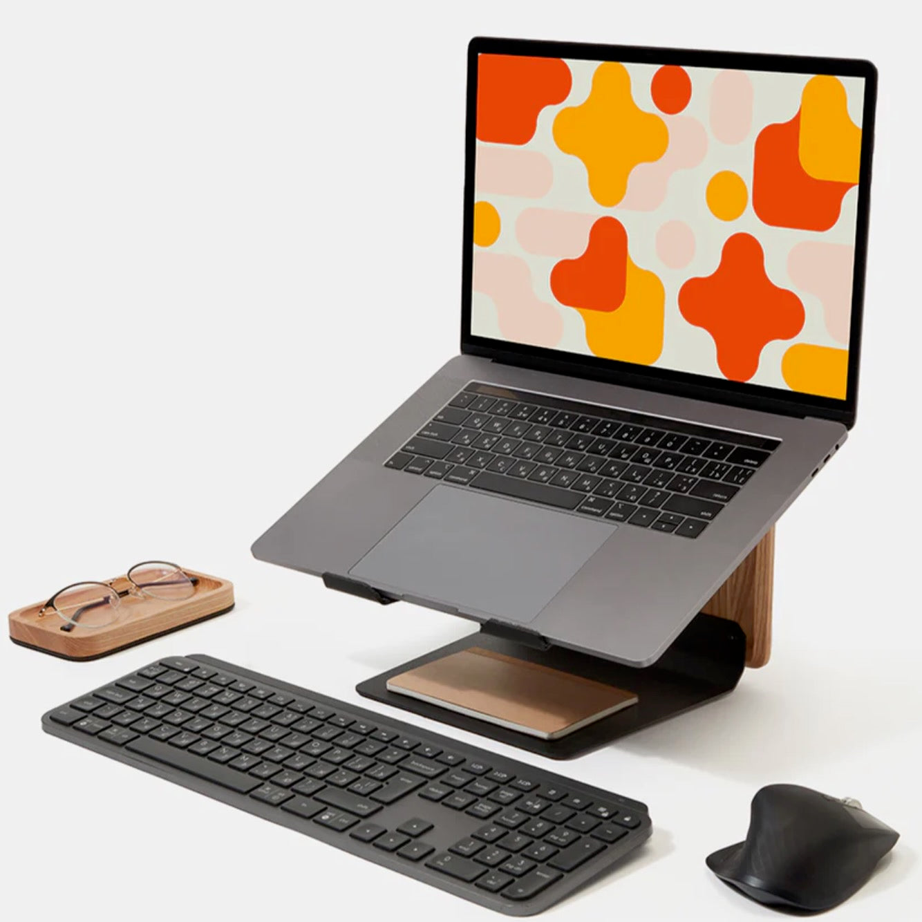 Laptop on ergonomic wooden stand with wireless keyboard, mouse, and desk accessories for home office setup