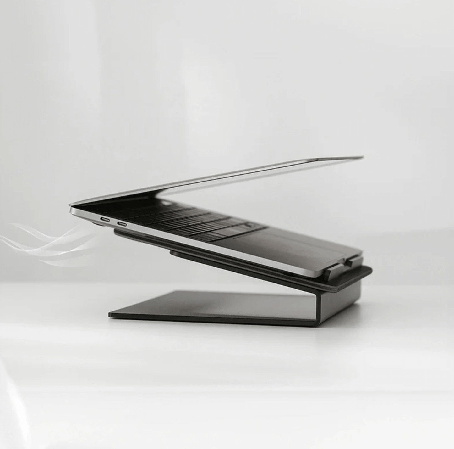 Laptop on a black stand against a white background, side view of classic laptop stand,